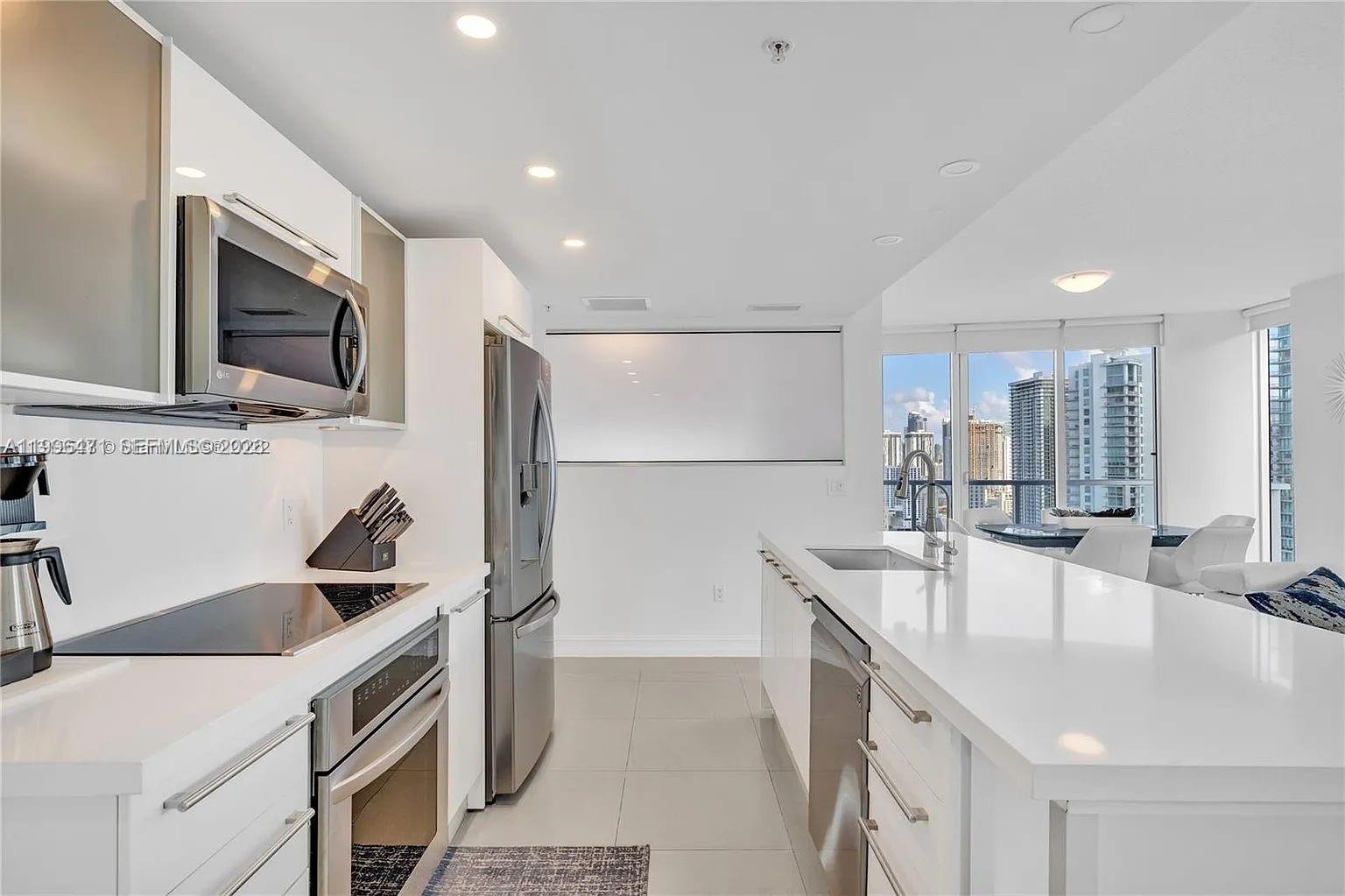 185 Southwest 7th Street, Unit 3611 Miami, FL 33130 - Photo 4 of 14 a kitchen with granite countertop a sink and a stove top oven with wooden floor