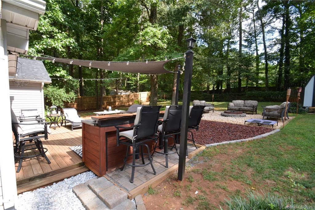 324 Radio Road, Unit 4 Charlotte, NC 28216 - Photo 16 of 19 a view of a patio with table and chairs potted plants with wooden floor and fence