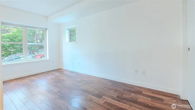 an empty room with wooden floor and windows