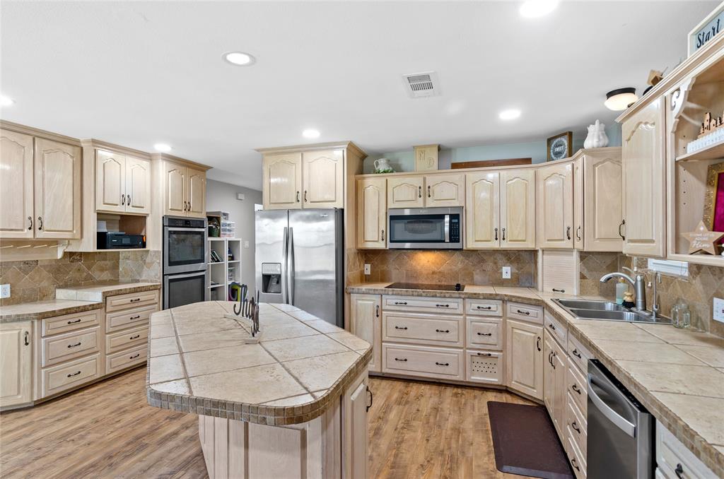 14728 Songbird Lane Haslet, TX 76052 - Photo 7 of 40 a kitchen with stainless steel appliances kitchen island granite countertop a stove top oven a sink a refrigerator with white cabinets and wooden floor