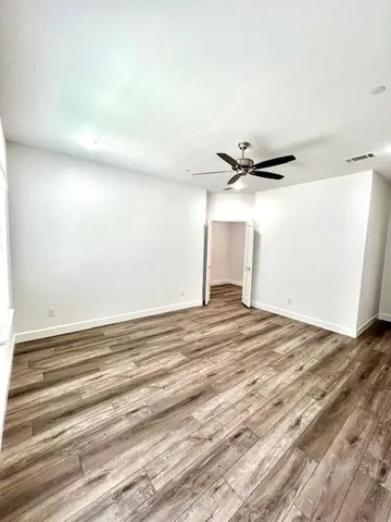 an empty room with wooden floor closet and windows