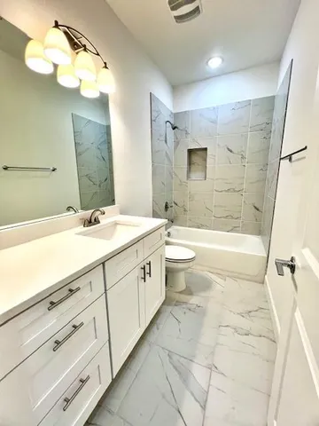 an empty room with wooden floor ceiling fan and windows