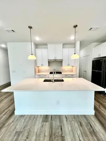 a large white kitchen with wooden floors