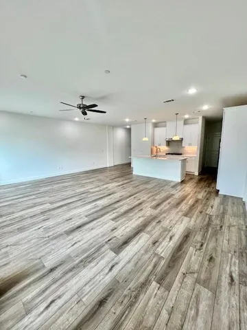 a large white kitchen with kitchen island a sink a stove and wooden floors