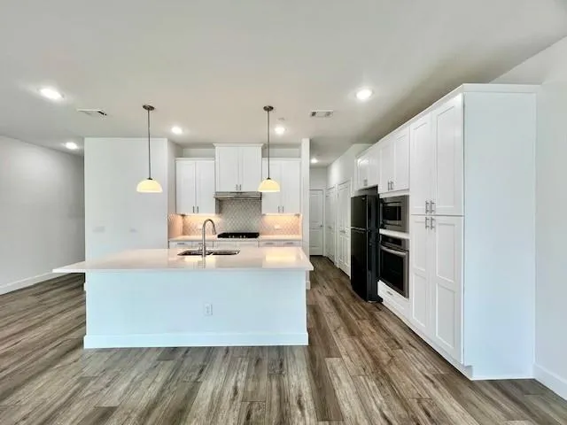 a kitchen with stainless steel appliances a stove a sink a refrigerator and chairs