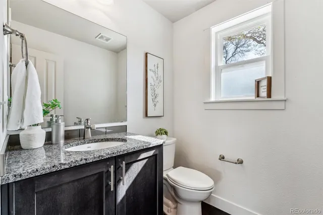 a bathroom with a granite countertop sink a toilet and a mirror