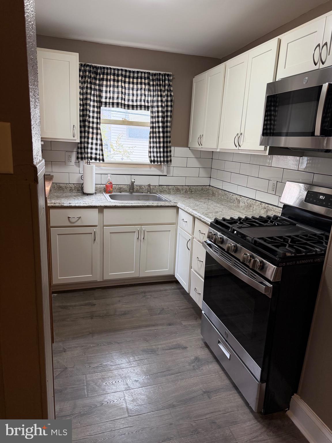 2519 Hobson Street Philadelphia, PA 19142 - Photo 2 of 8 a kitchen with granite countertop a stove a sink and a microwave