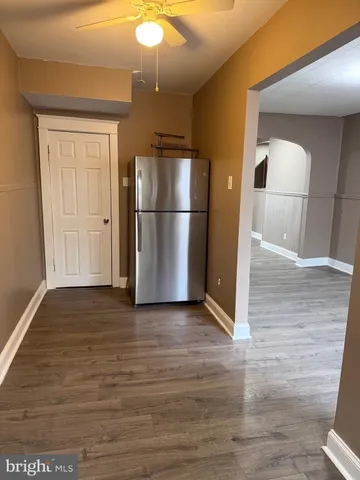 a view of a refrigerator in kitchen and an empty room