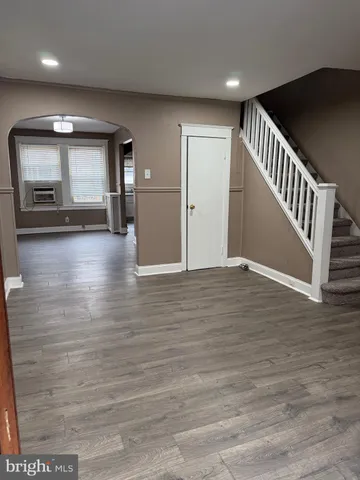 a view of an empty room with wooden floor and staircase