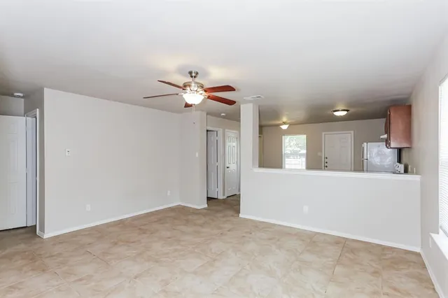 a view of an empty room with chandelier fan