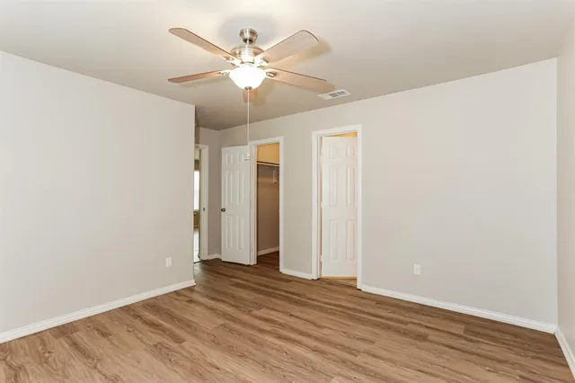an empty room with wooden floor and ceiling fan