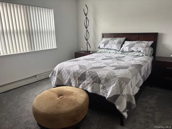 a bed sitting in a bedroom next to a window and a chair