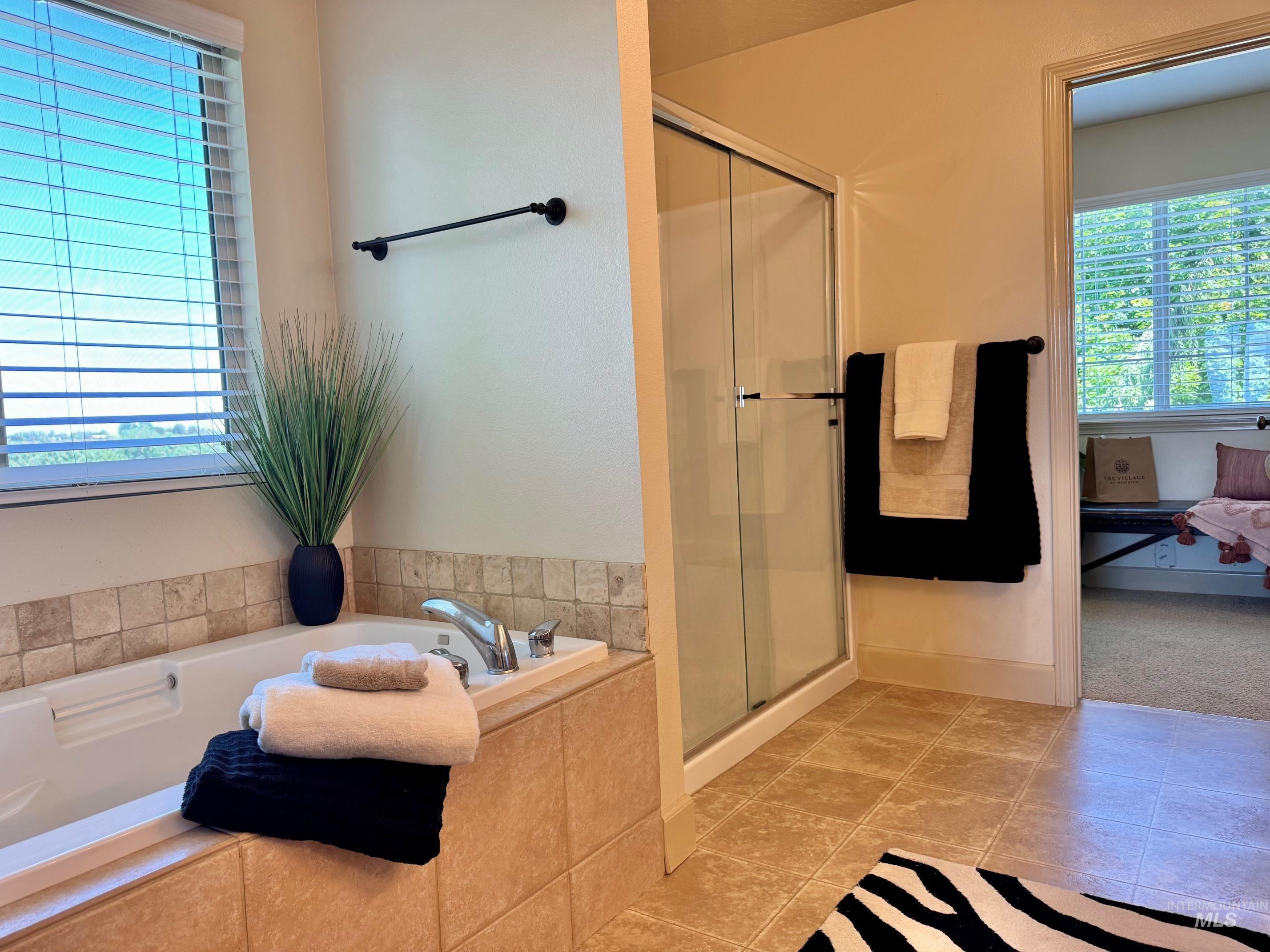 9299 Kemp Road Middleton, ID 83644 - Photo 27 of 50 Soaking tub with tile surround, separate glass-enclosed shower, and tile flooring