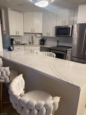 a kitchen with stainless steel appliances a sink a stove a refrigerator a microwave a sink and cabinets