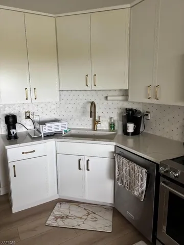 a kitchen with granite countertop a sink cabinets and stainless steel appliances