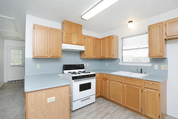 a kitchen with stainless steel appliances granite countertop white cabinets a sink a stove a refrigerator and island with wooden floors