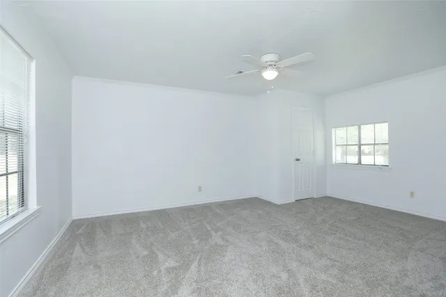 an empty room with a window and ceiling fan
