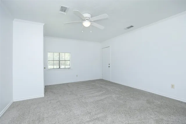 an empty room with windows and ceiling fan