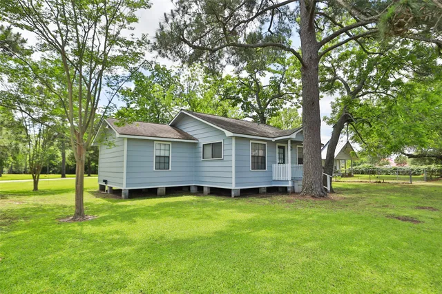 a view of a yard in front of a house with large trees
