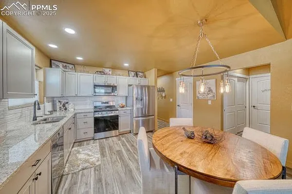a kitchen with a dining table chairs cabinets and stainless steel appliances