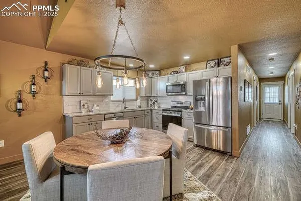 a kitchen with stainless steel appliances kitchen island granite countertop a refrigerator a stove a sink dishwasher and white cabinets with wooden floor