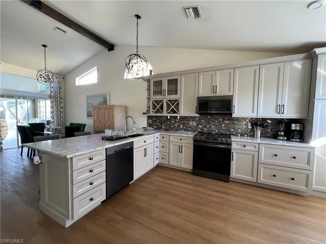 a large kitchen with cabinets a sink dishwasher a dining table and chairs