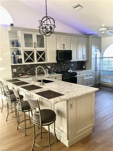a kitchen with stainless steel appliances granite countertop a stove top oven a sink dishwasher a dining table and chairs with wooden floor