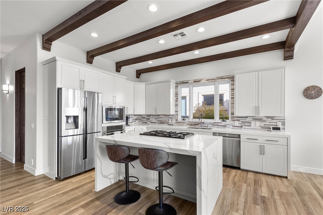 3 Rue Allard Way Henderson, NV 89011 - Photo 12 of 49 Kitchen featuring light stone counters, a center island, visible vents, appliances with stainless steel finishes, and a sink