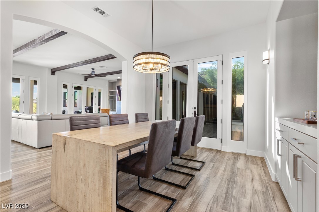 3 Rue Allard Way Henderson, NV 89011 - Photo 18 of 49 Dining area featuring light wood finished floors, baseboards, visible vents, arched walkways, and beam ceiling
