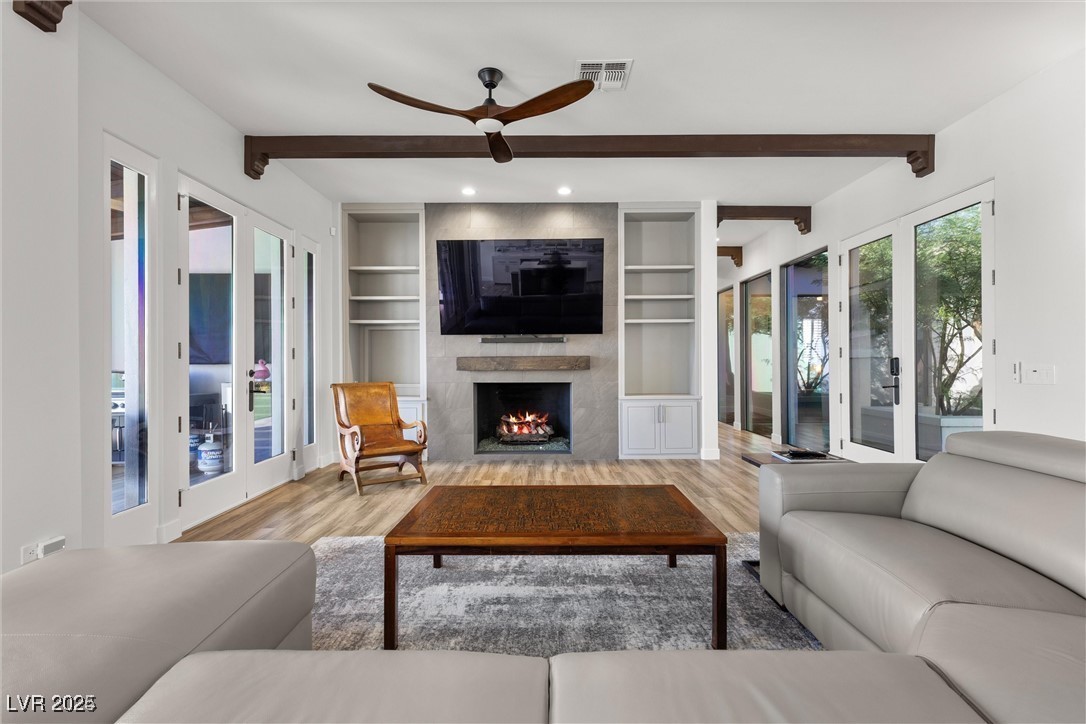 3 Rue Allard Way Henderson, NV 89011 - Photo 9 of 49 Living area featuring a large fireplace, visible vents, wood finished floors, beamed ceiling, and built in shelves