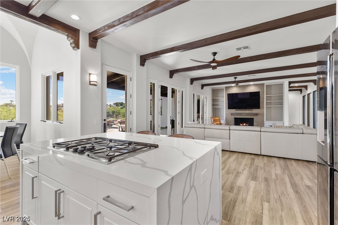 3 Rue Allard Way Henderson, NV 89011 - Photo 10 of 49 Kitchen featuring stainless steel gas cooktop, a large fireplace, visible vents, and a healthy amount of sunlight