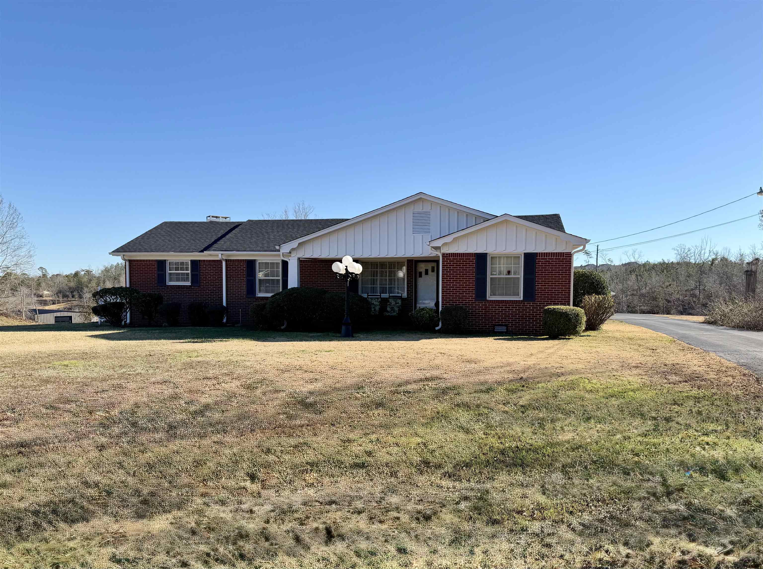Ranch-style home with brick siding, a front lawn, and board and batten siding