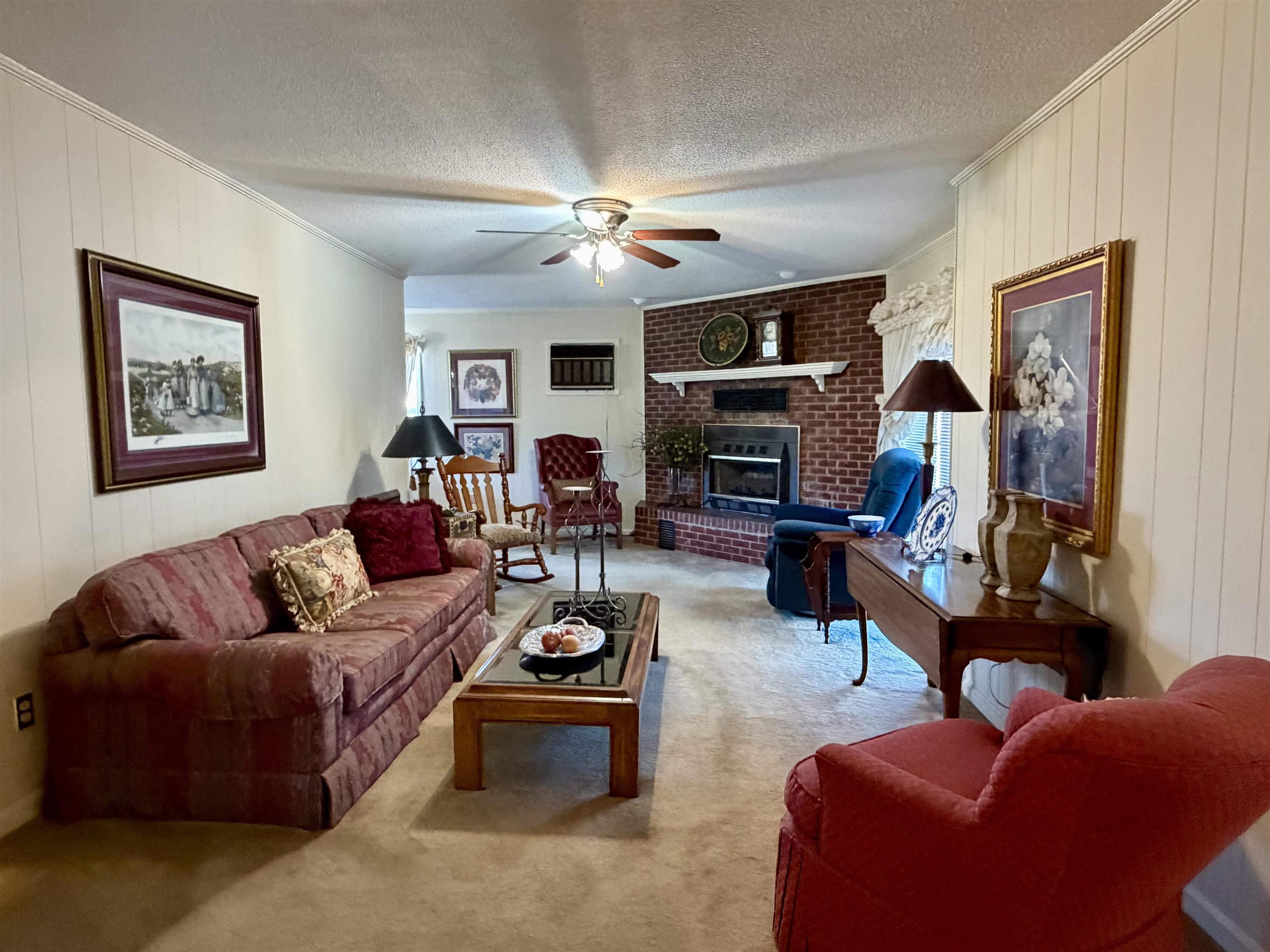 192 New Bethel Road Selmer, TN 38375 - Photo 13 of 27 Living room with wood walls, ornamental molding, a textured ceiling, a fireplace, and a ceiling fan