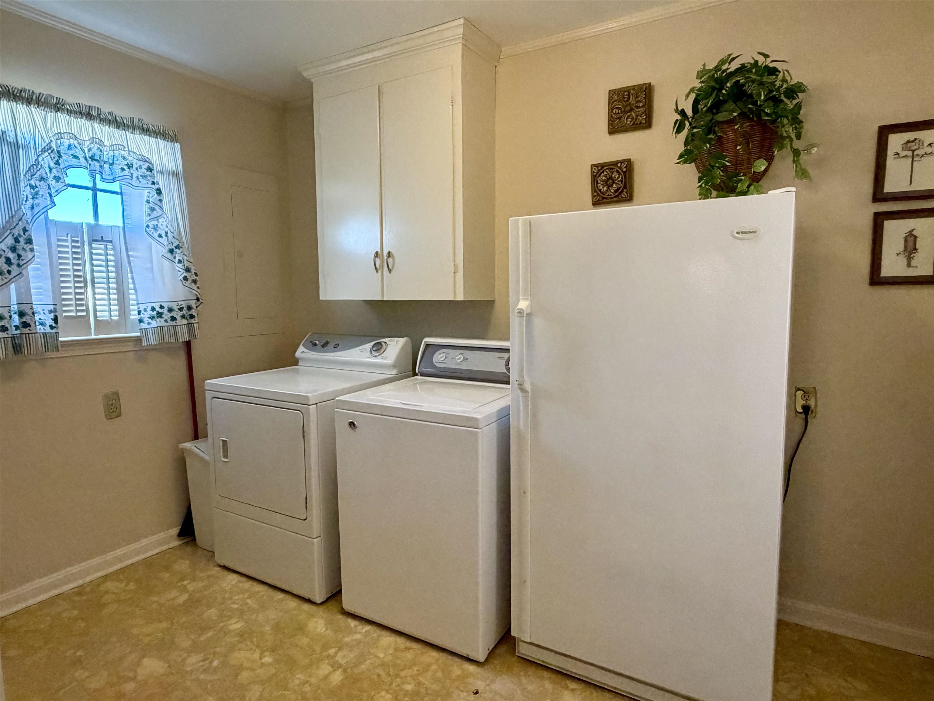 192 New Bethel Road Selmer, TN 38375 - Photo 24 of 27 Laundry room featuring cabinet space, washing machine and clothes dryer, light flooring, and ornamental molding