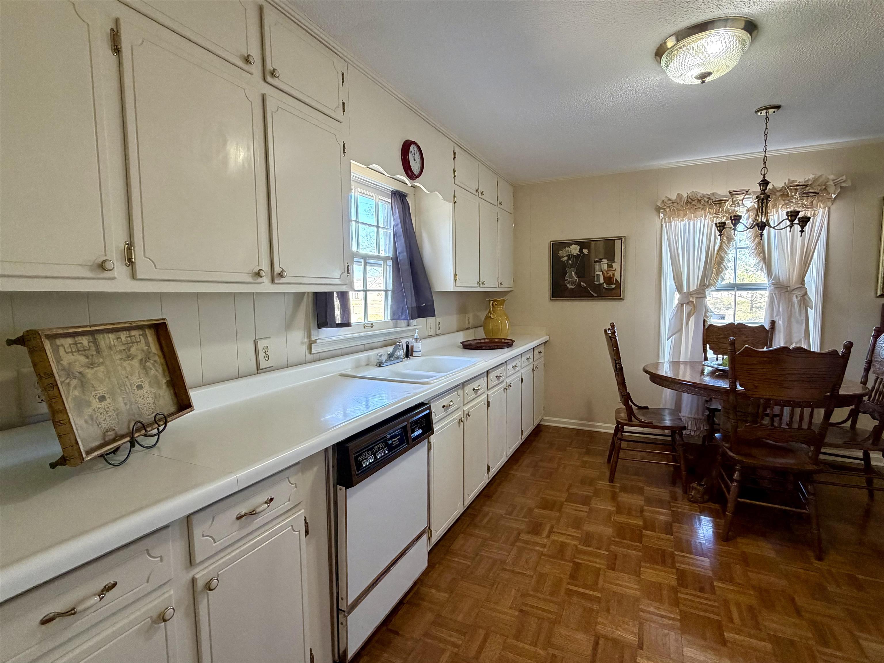 192 New Bethel Road Selmer, TN 38375 - Photo 6 of 27 Kitchen featuring white dishwasher, parquet floors, pendant lighting, white cabinets, and a textured ceiling