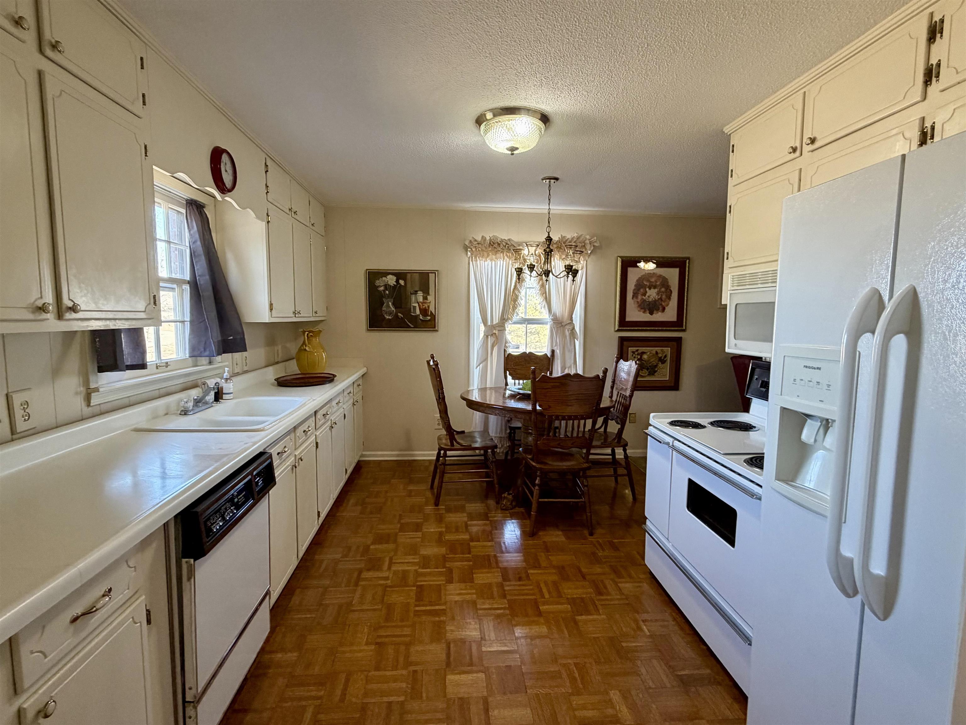 192 New Bethel Road Selmer, TN 38375 - Photo 7 of 27 Kitchen featuring white appliances, parquet flooring, light countertops, a chandelier, and a textured ceiling