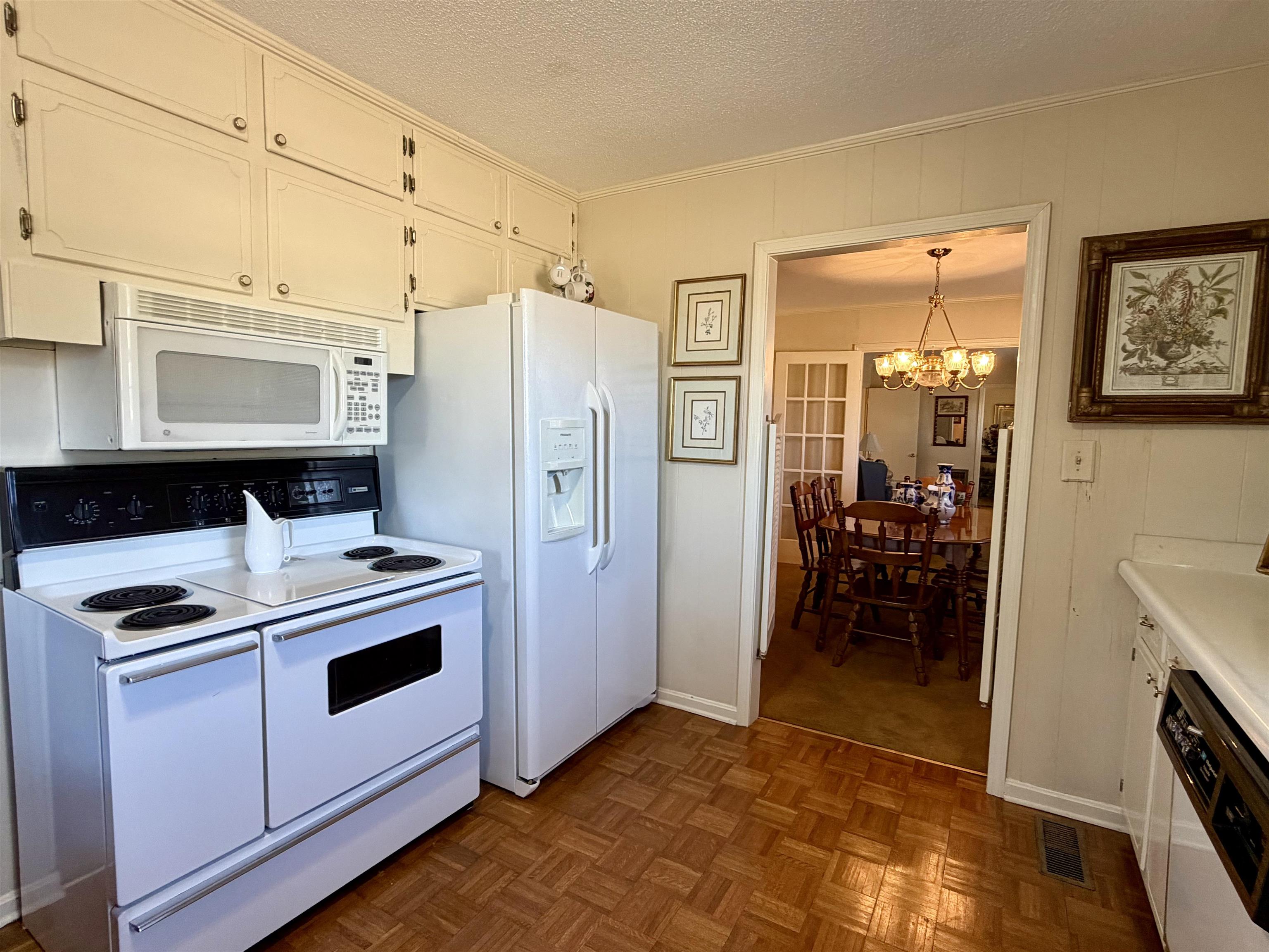192 New Bethel Road Selmer, TN 38375 - Photo 8 of 27 Kitchen with white appliances, light countertops, a textured ceiling, a chandelier, and parquet flooring