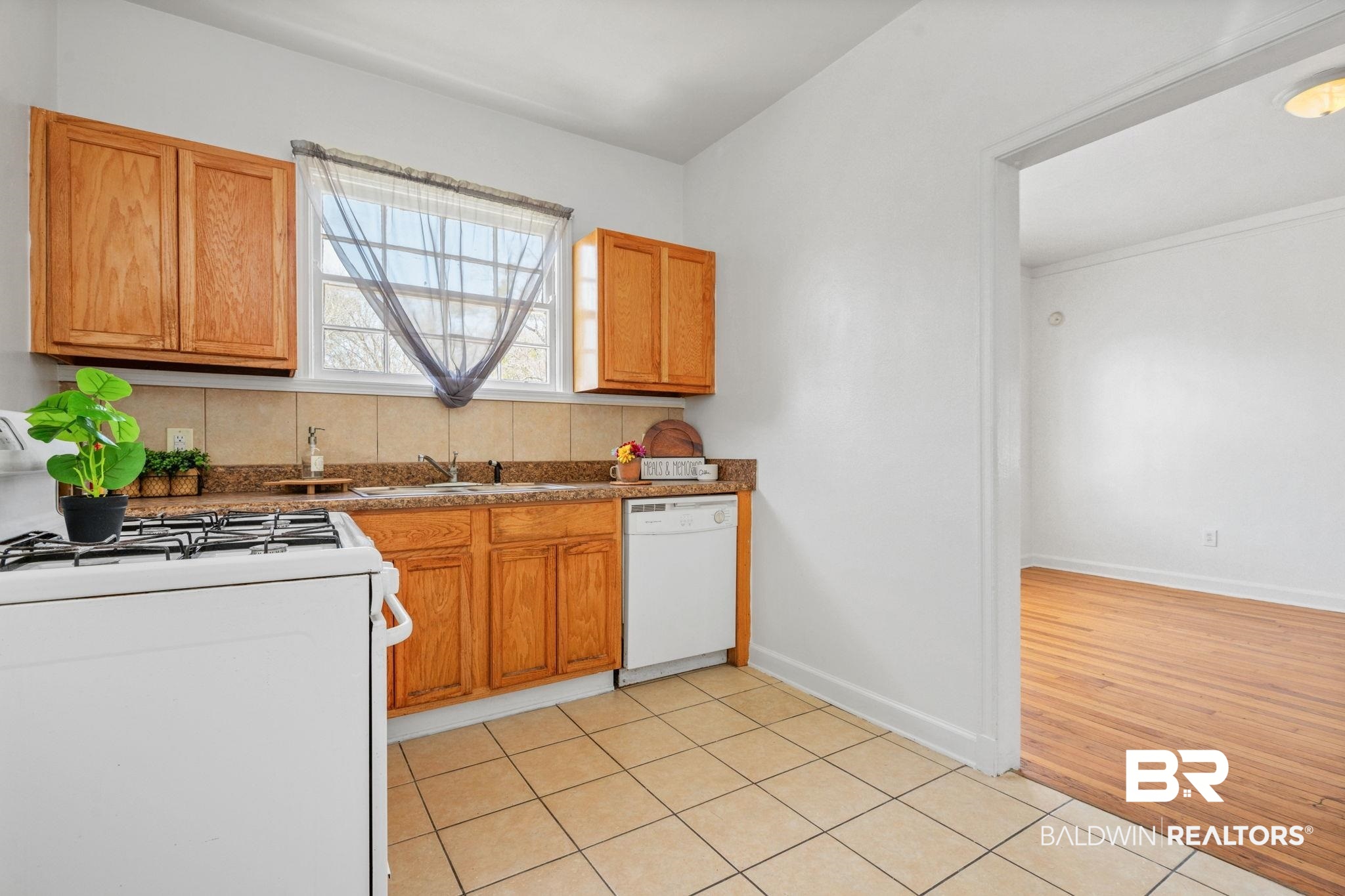 1707 Church Street Mobile, AL 36604 - Photo 22 of 43 Kitchen with a sink, white appliances, light tile patterned floors, decorative backsplash, and baseboards