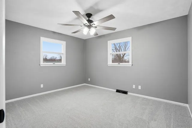 an empty room with windows and fan