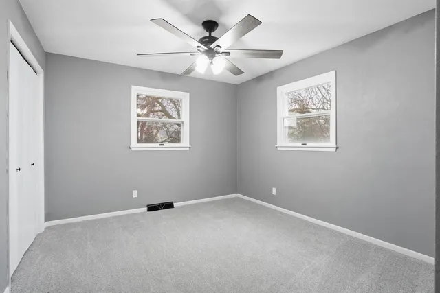 an empty room with windows and fan