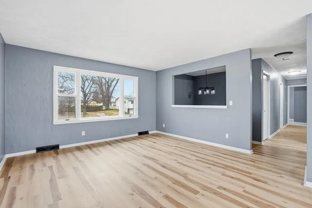 a view of an empty room with wooden floor and window