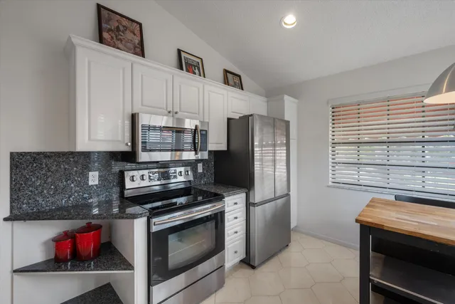 a kitchen with granite countertop a sink and a white cabinets