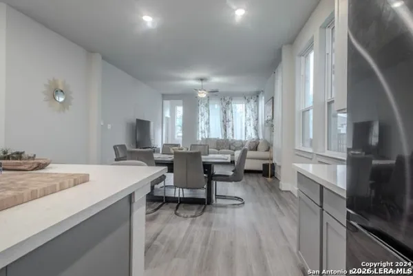 a large white kitchen with a sink and dishwasher a stove top oven with wooden floor