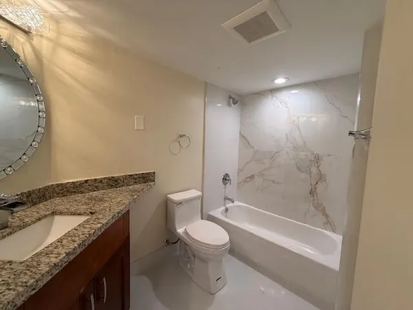 a bathroom with a granite countertop toilet a sink and a mirror