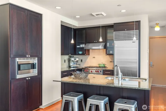 a kitchen with kitchen island granite countertop wooden cabinets and refrigerator