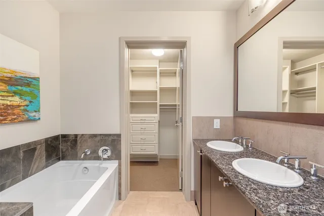 a bathroom with a granite countertop tub sink and mirror
