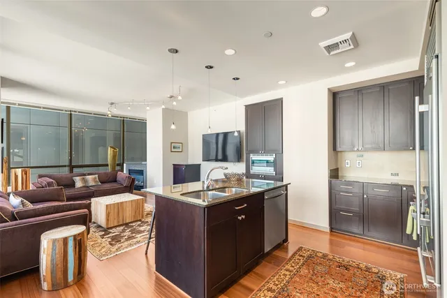 a kitchen with stainless steel appliances kitchen island granite countertop a sink and a refrigerator