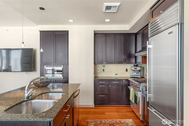 a kitchen with kitchen island granite countertop a sink stainless steel appliances and cabinets