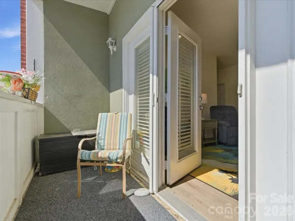 a porch with a chair and a potted plant next to a window