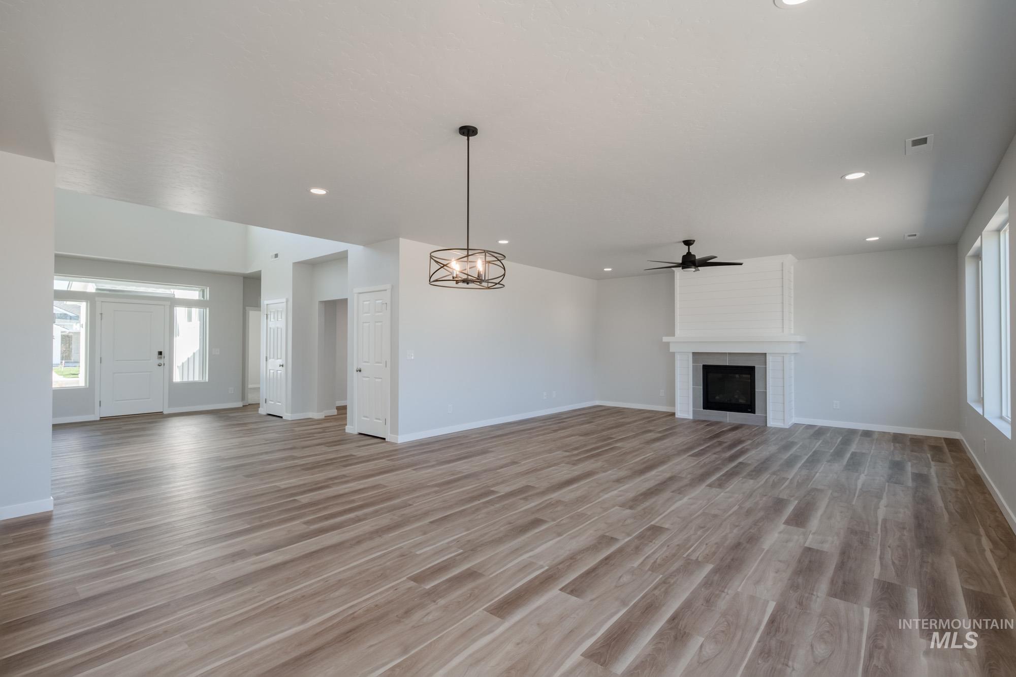 3170 South Maple Rnch Way Nampa, ID 83686 - Photo 10 of 32 Unfurnished living room featuring plenty of natural light, a tiled fireplace, light wood-type flooring, a chandelier, and recessed lighting